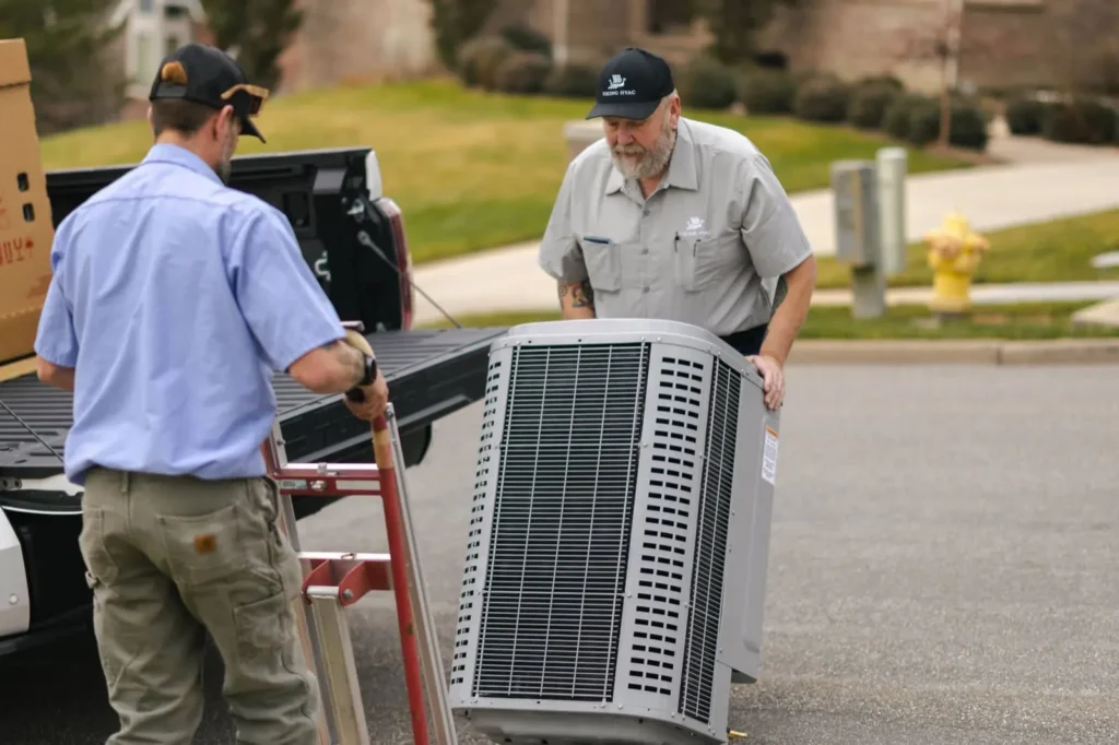 Viking Heating and Air technicians carrying a new AC condenser to a job site